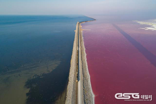 2020년 10월 그레이트 솔트레이크를 가로지르는 철길을 경계로 물색이 짙은 녹색과 붉은색으로 나뉘었다. 물의 색이 다른 것은 염분 함량이 높을수록 번성하는 미생물 때문이다레이트솔트 호수,"©&nbsp;제공: 한국일보.&nbsp;